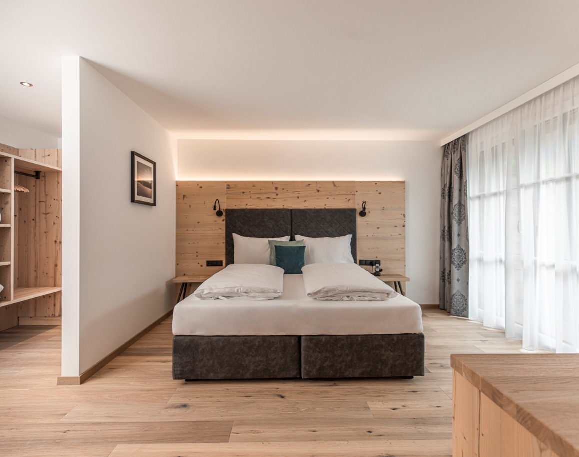 Hotelzimmer in der Lodge Emmy mit Doppelbett, großem Fenster und hellem Holzboden
