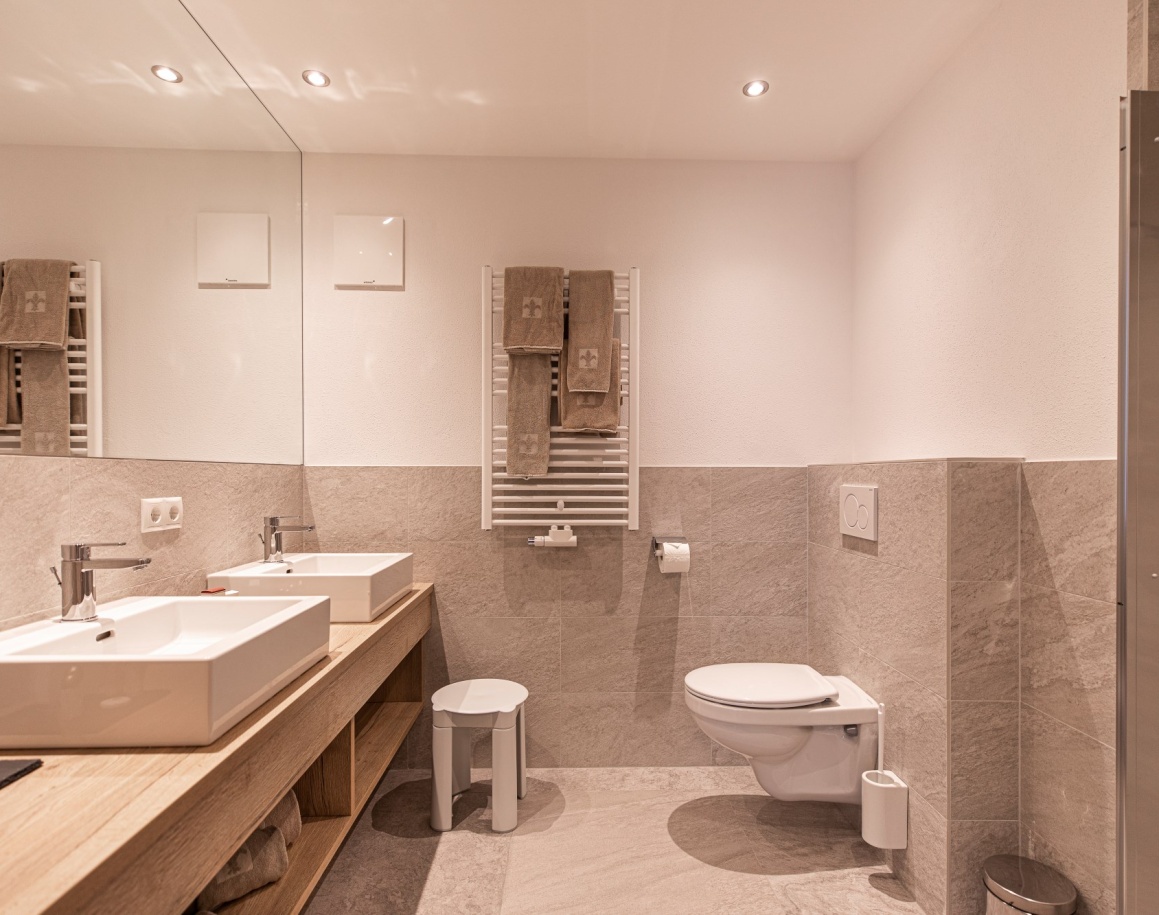 Modernes Badezimmer mit Doppelwaschbecken, großer Spiegel und WC