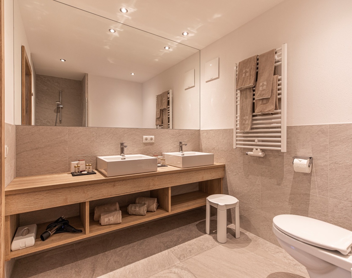 Modernes Badezimmer mit Doppelwaschbecken, großem Spiegel und WC in hellen Tönen