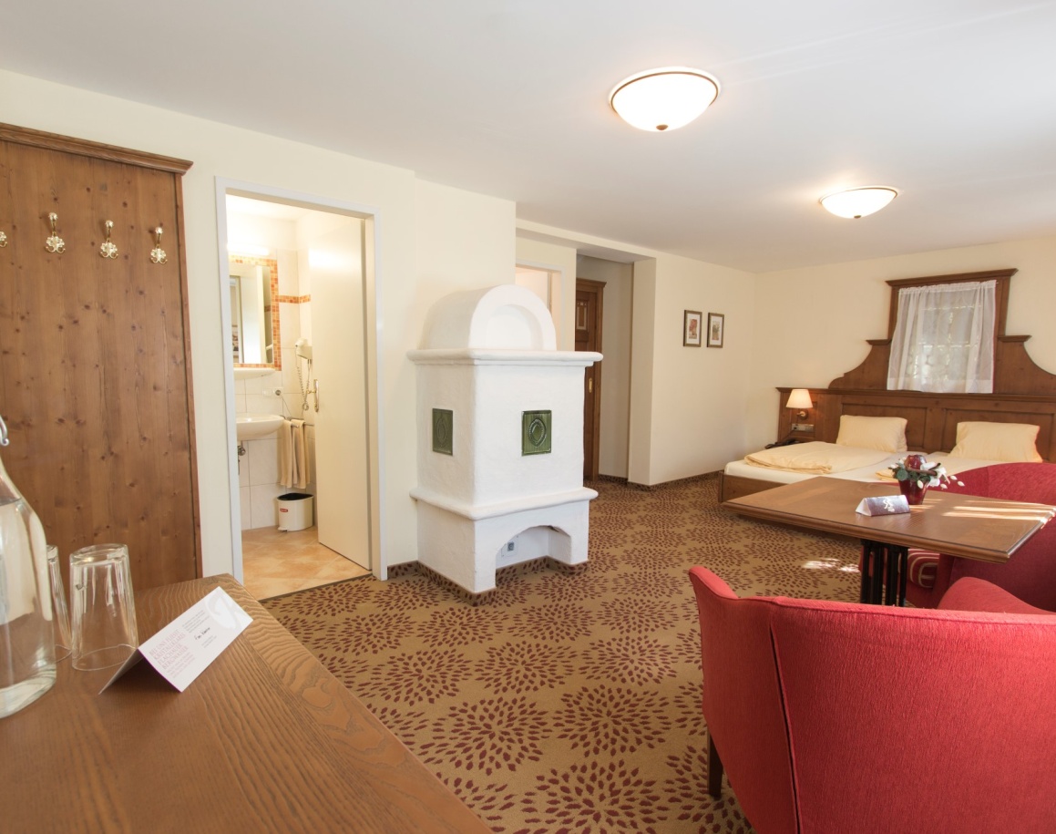 Gemütliches Schlafzimmer mit Doppelbett, Kamin, roten Sesseln und direktem Badzugang