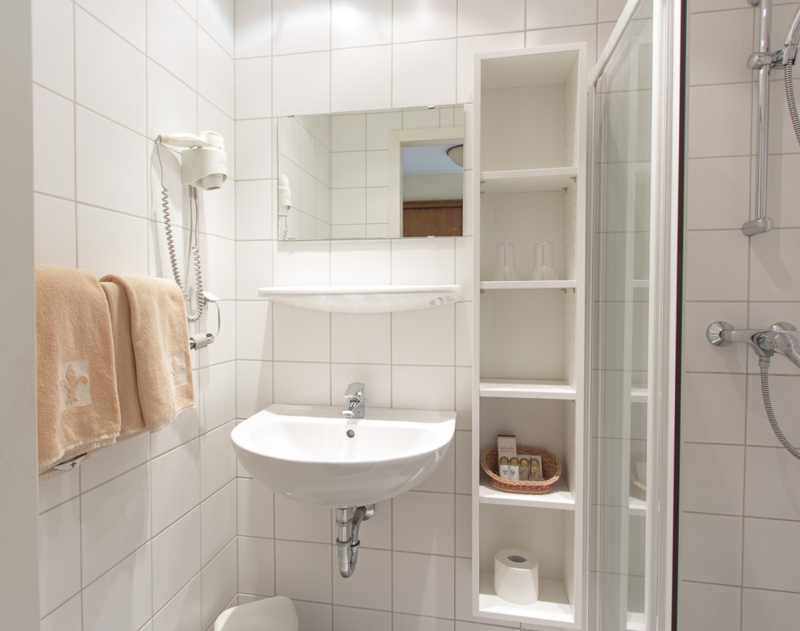 Kleines Badezimmer mit Waschbecken, Dusche und weißen Fliesen