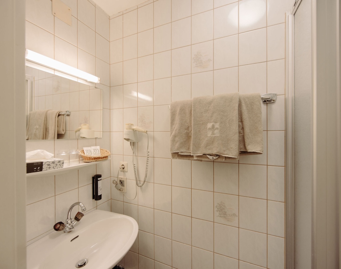 Kleines Badezimmer mit weißen Fliesen, Waschbecken und einem Regal