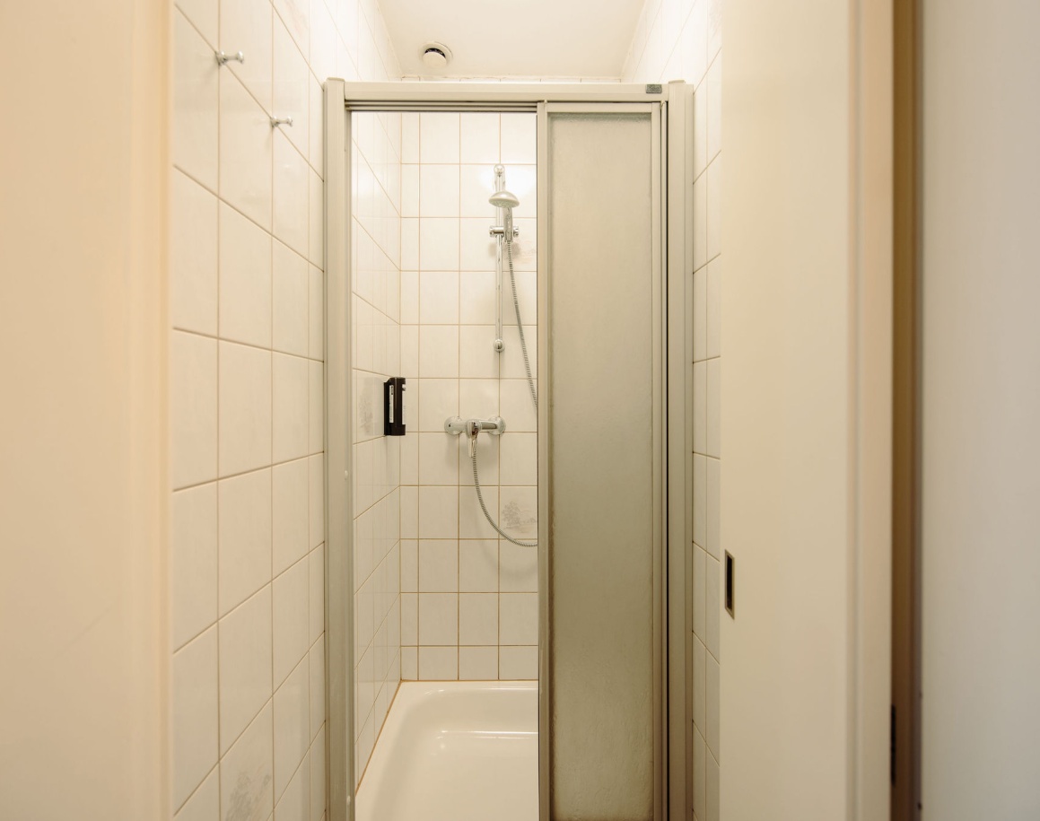 Duschkabine mit Fliesenwänden und Glasfalttür