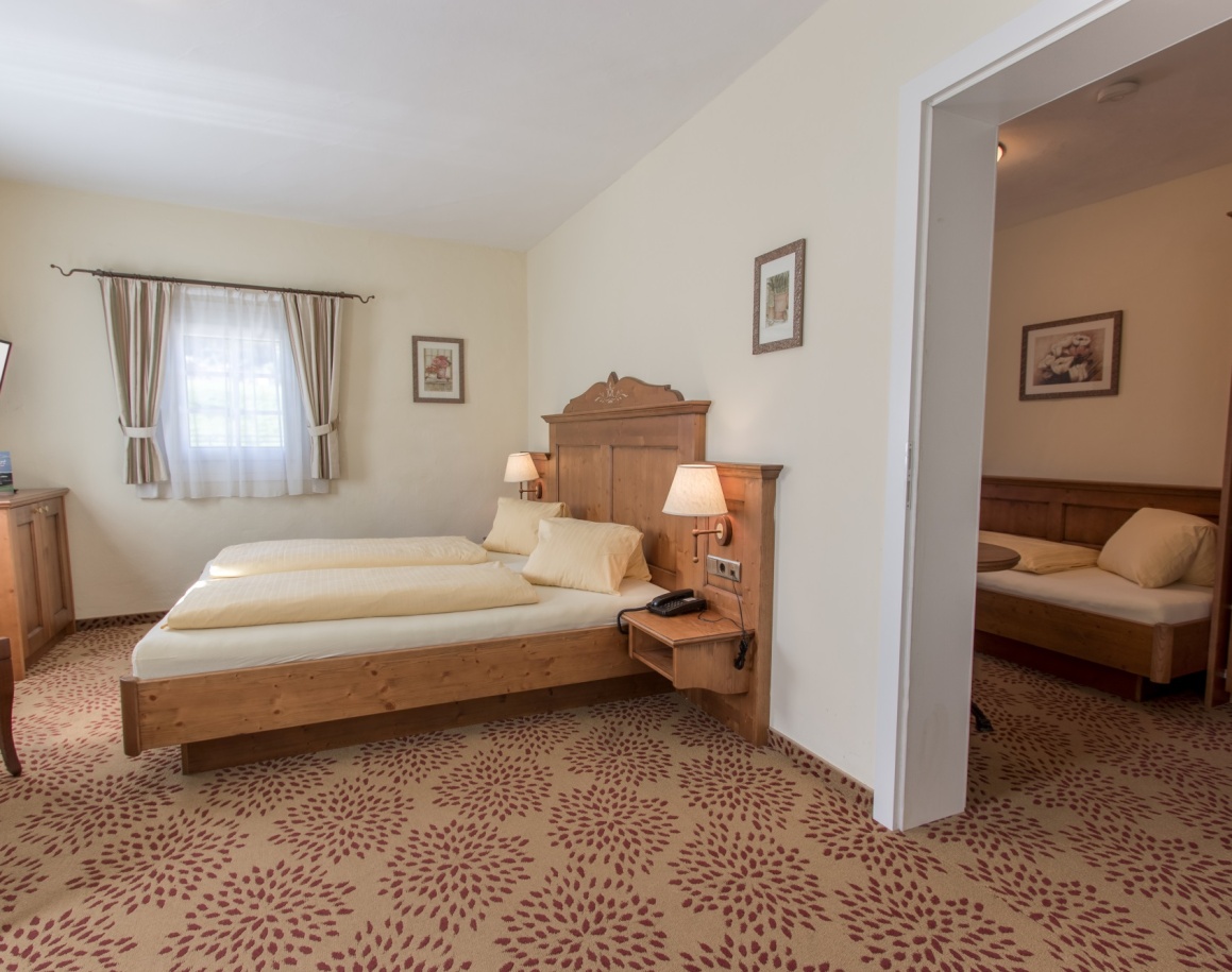 Ein gemütliches Schlafzimmer mit Doppelbett und angrenzendem Einzelbett in hellem Dekor