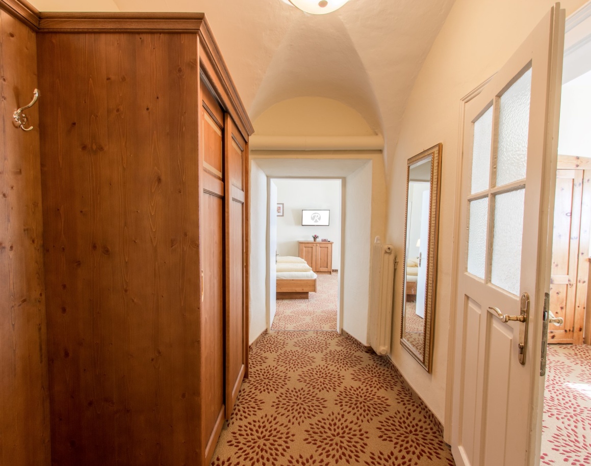 Flur mit Teppichboden, Spiegel, Schrank und Blick auf Schlafzimmer im Hintergrund