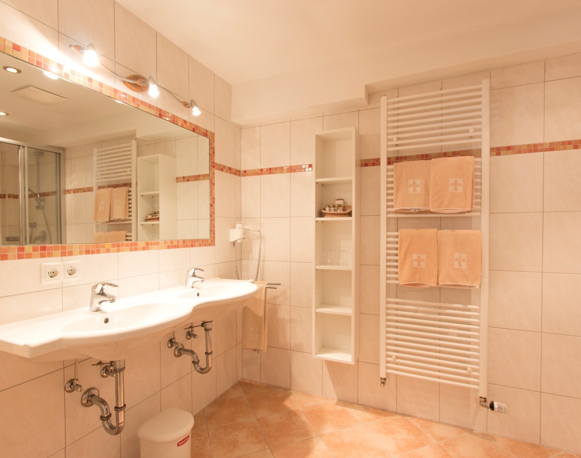 Badezimmer mit Doppelwaschbecken, großem Spiegel und hellen Fliesen