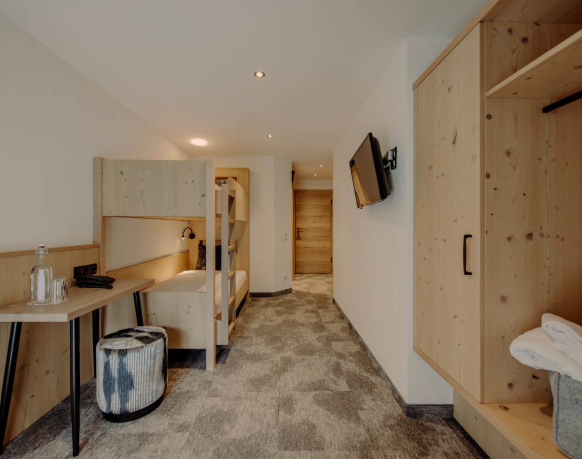 Einblick ins Bunk Zimmer mit Kleiderschrank, Schreibtisch und Bett im Hintergrund