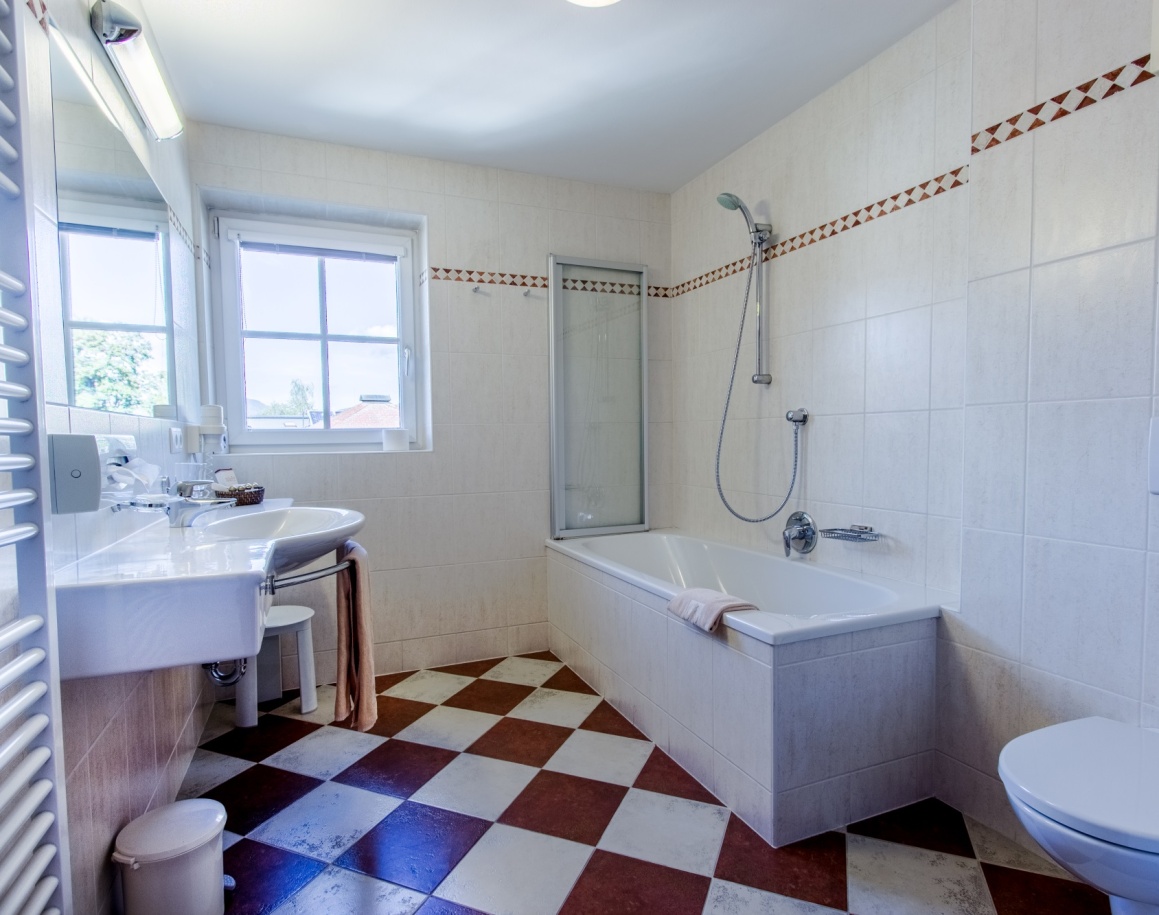 Helles Badezimmer mit Dusche, Waschbecken und schwarz-weiß karierten Fliesen