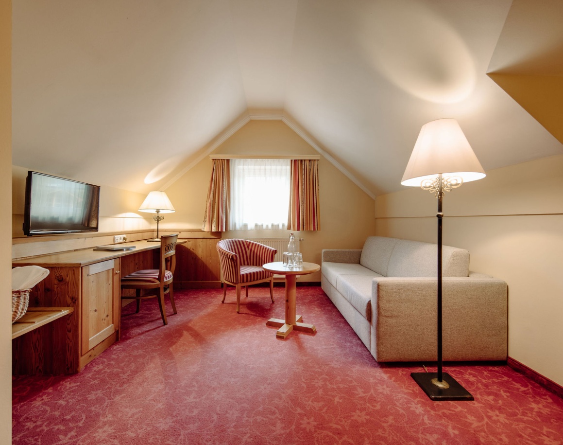 Charmantes Dachzimmer mit Sofa, Teppichboden und Stehlampe