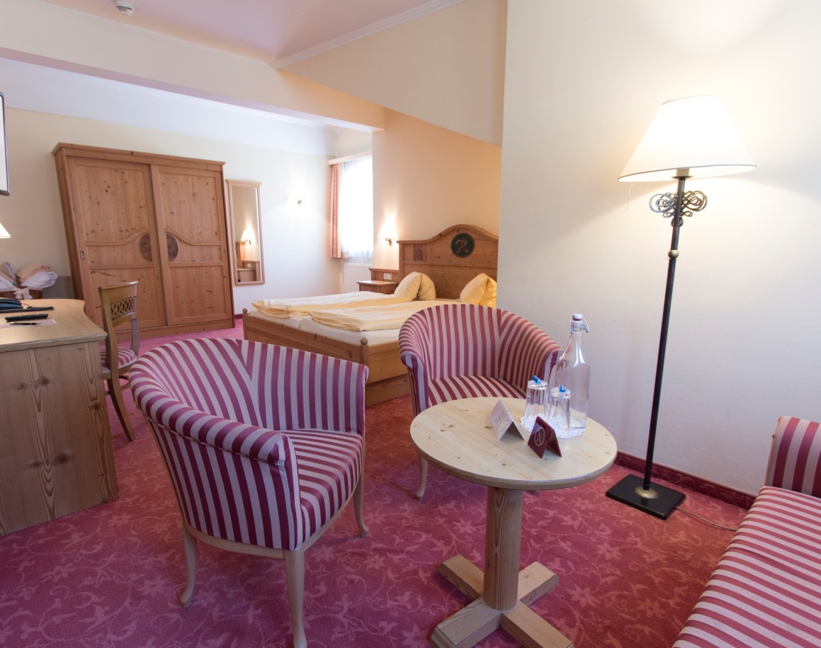 Gemütliche Sitzecke im Hotelzimmer mit Tisch, Stühlen und Blumenstrauß