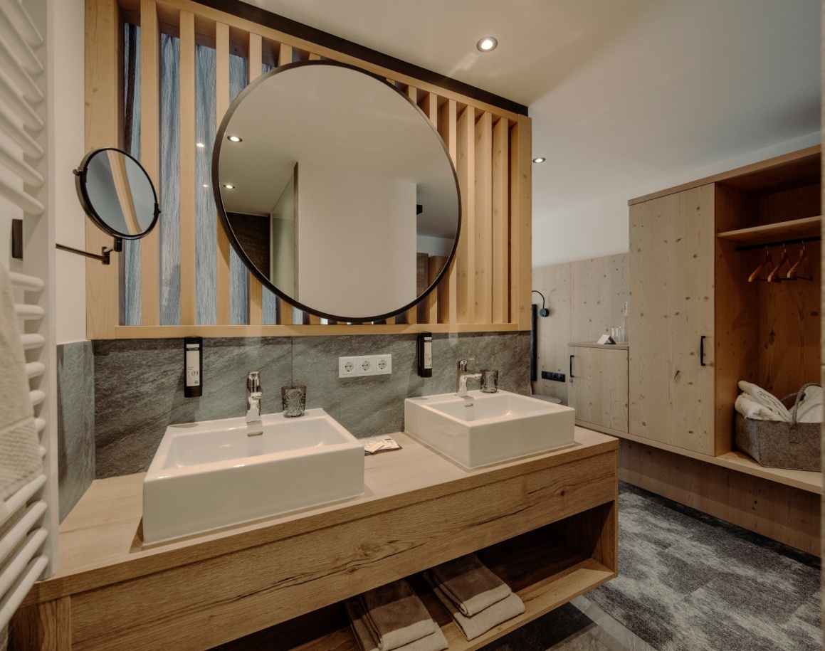Helles Hotelbadezimmer mit Doppelwaschbecken, Spiegel und Holzdetails