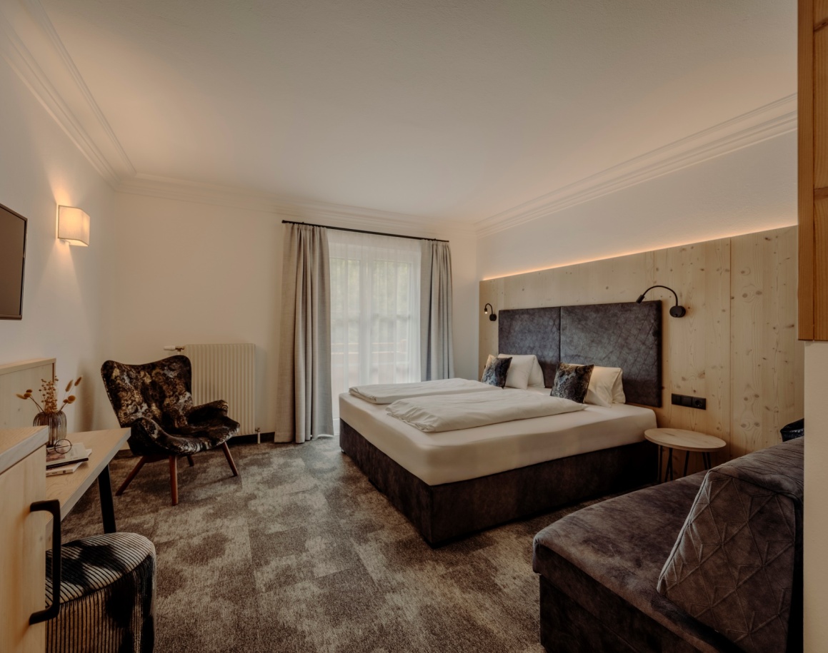 Komfortables Hotelzimmer mit Doppelbett, Ohrensessel und Fernseher