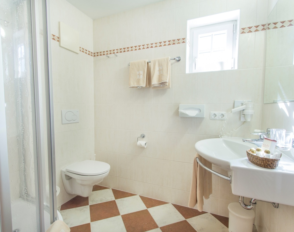 Helles Badezimmer mit Dusche, WC, Waschbecken und Handtüchern an der Wand