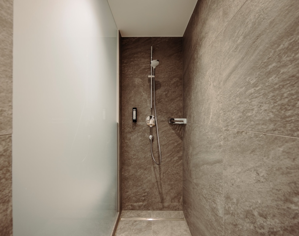 Moderne Dusche mit Steinfliesenwänden im Hotel Resl