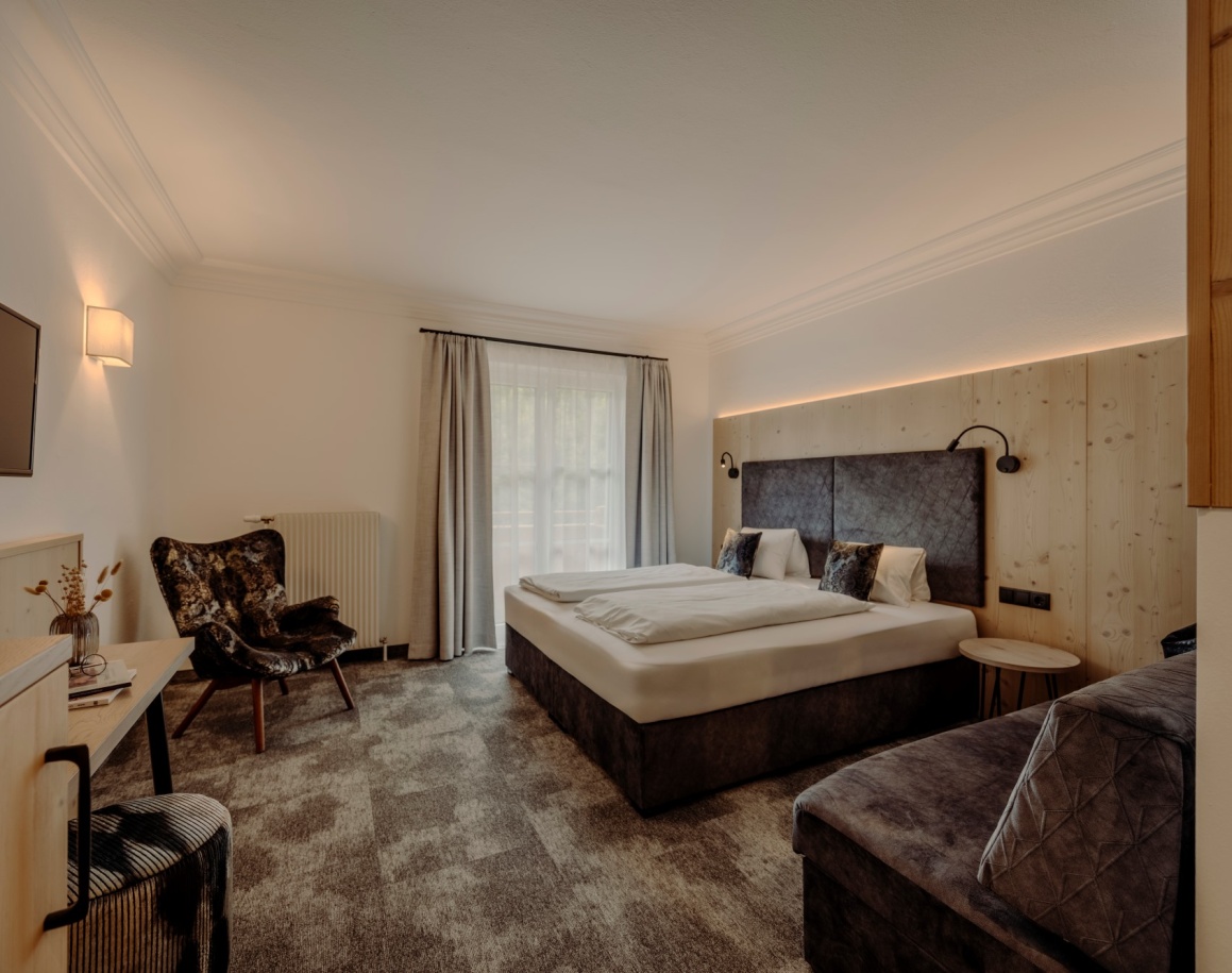 Helles Hotelzimmer mit Doppelbett, Sesseln und großem Fenster