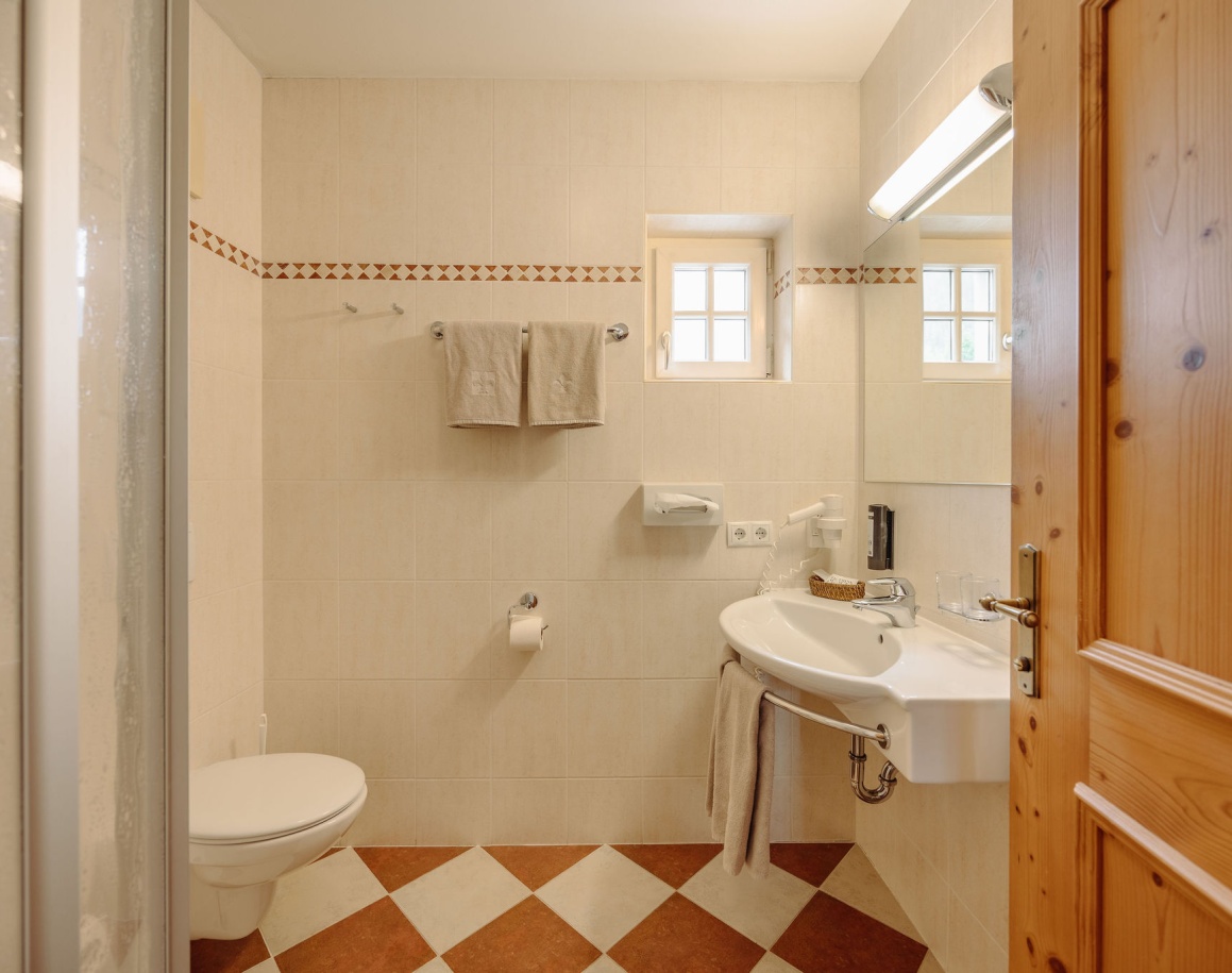 Helles Badezimmer mit Fenster, Dusche und Toilette im Hotel Resl