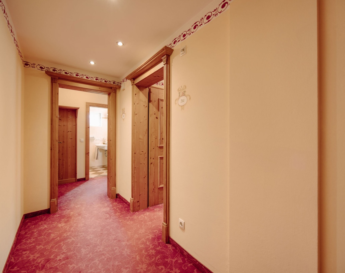 Ein mit Teppich ausgelegter Flur mit Holztüren und verzierten Wänden im Hotel Resl