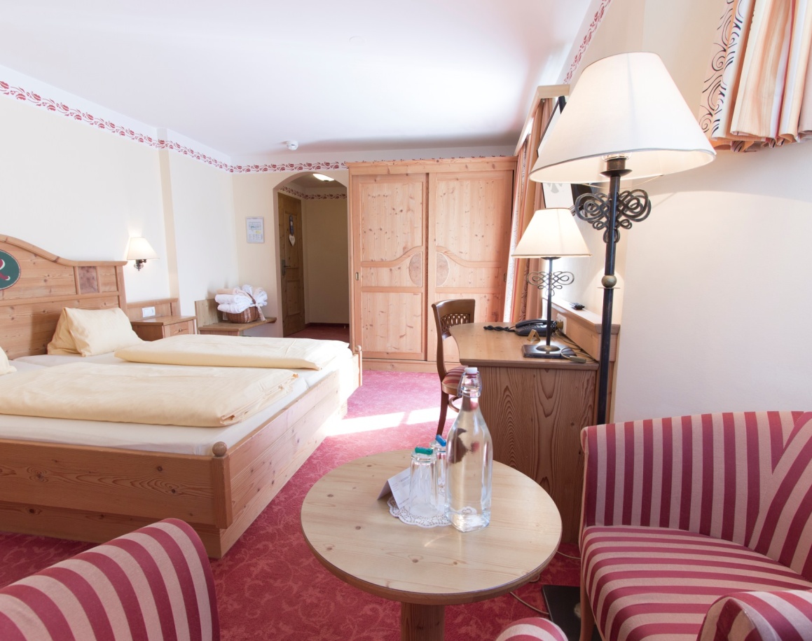 Ein gemütliches Hotelzimmer mit Doppelbett, Schreibtisch und gestreiften Sesseln