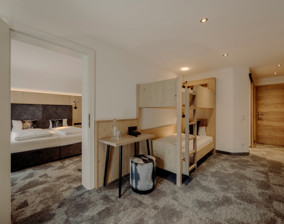 Helles Hotelzimmer mit Doppelbett und Stockbett