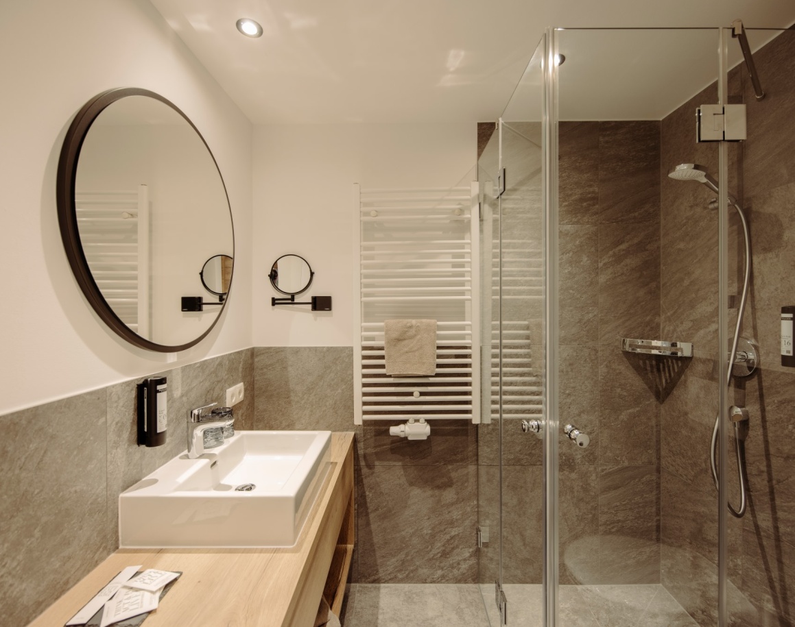 Modernes Hotelbadezimmer mit Glasdusche, Waschbecken und Spiegel