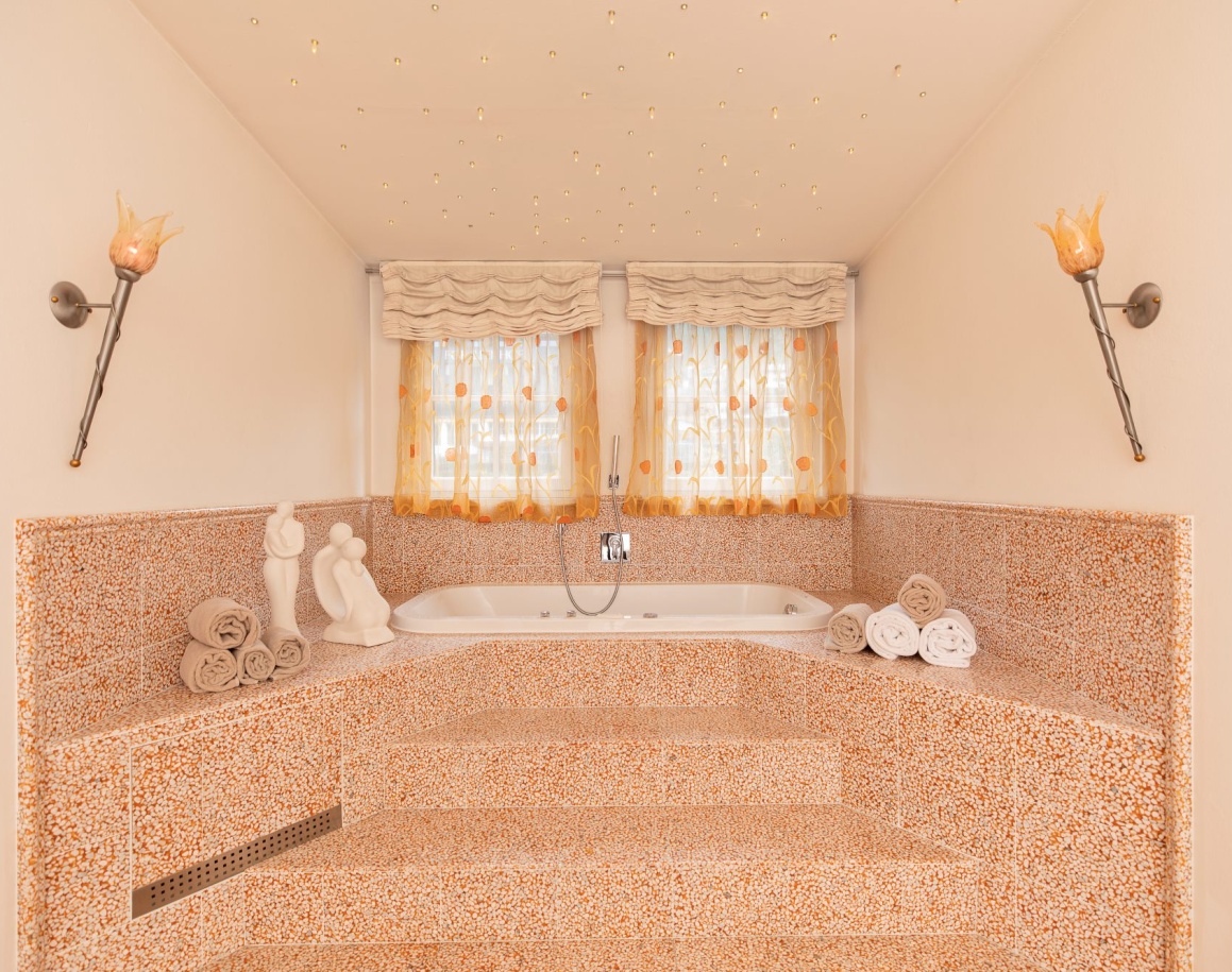 Luxuriöse eingebaute Badewanne mit dekorativen Handtüchern und Vorhängen