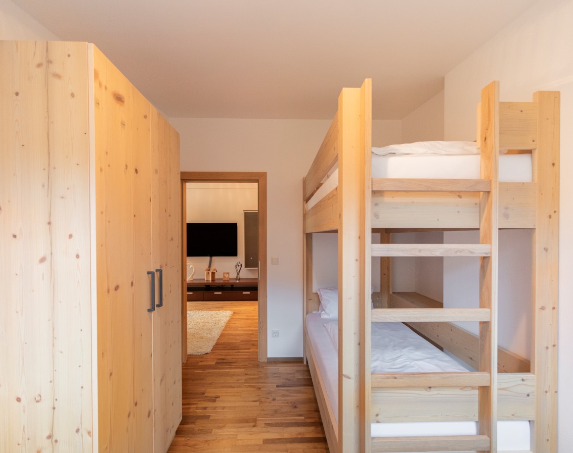Zimmer mit Etagenbett und Holzschränken, Blick ins Wohnzimmer